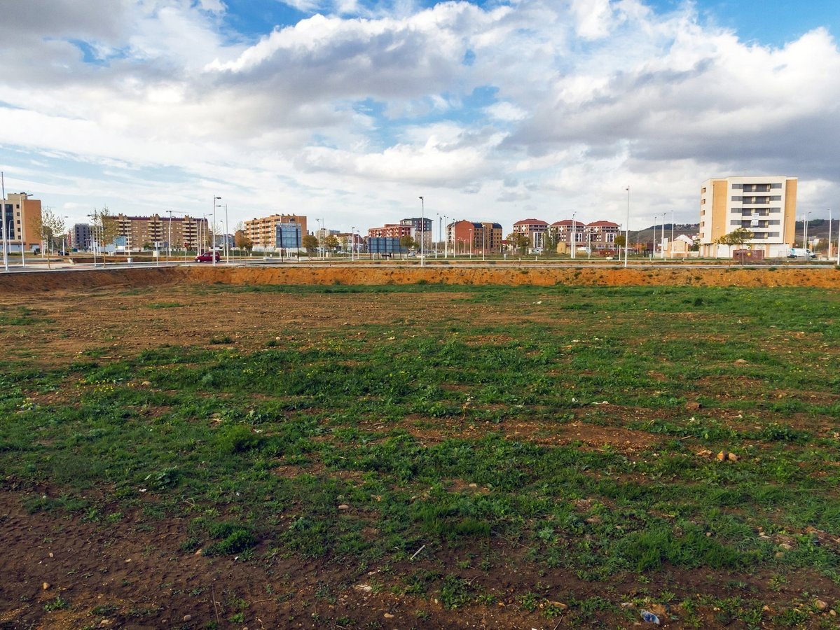 Freies Baugrundstück in Rheine mit Wohnbebauung im Hintergrund.
