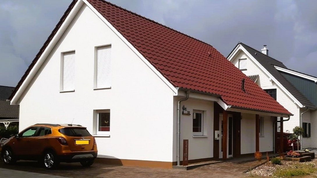 Einfamilienhaus mit rotem Satteldach und weißer Fassade – Massivhaus von Thielker MassivHaus im Münsterland