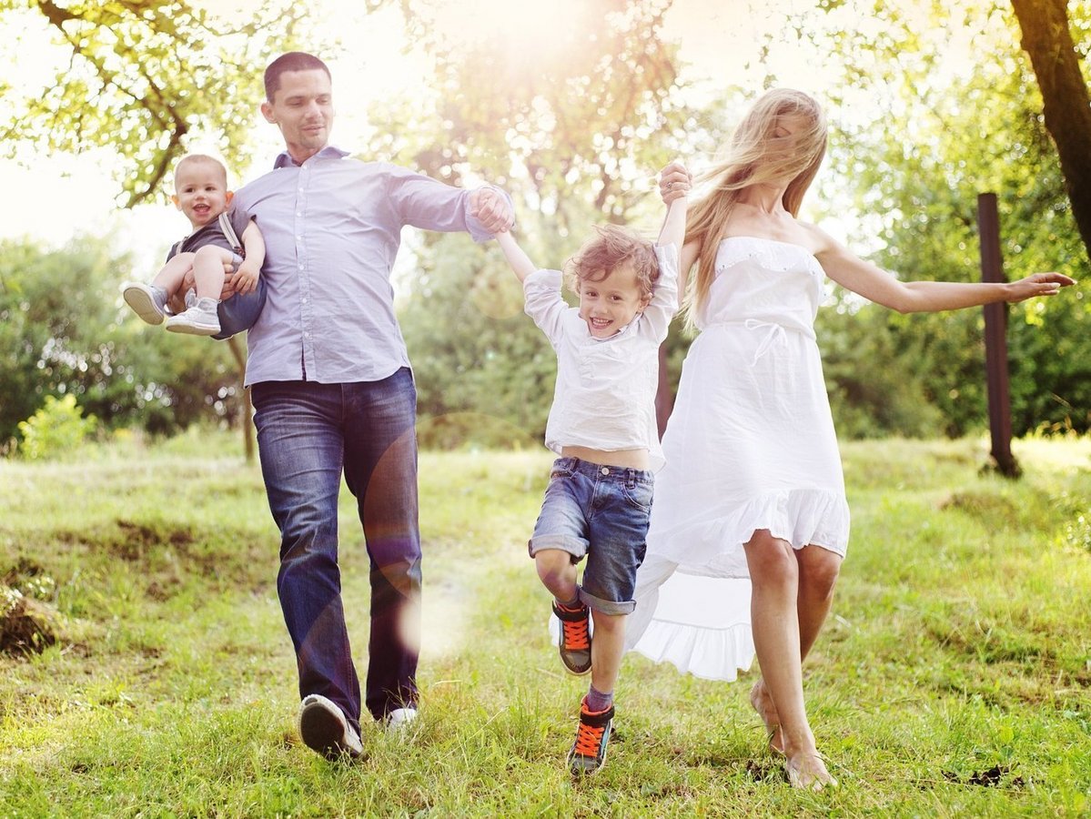Familienfreundlich wohnen im Landkreis Emsland mit Thielker MassivHaus Familie mit zwei Kindern läuft gemeinsam durch eine grüne Naturlandschaft im Landkreis Emsland