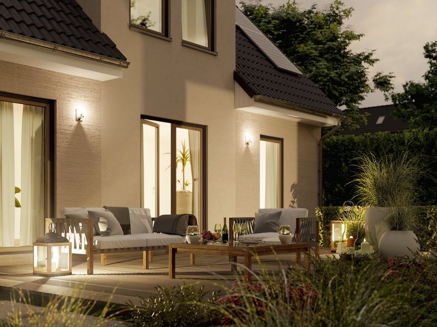 Genießen Sie die Detailansicht der Terrasse des Einfamilienhauses Flair 134 bei Abendstimmung mit bodentiefen Fenstern für einen malerischen Blick in den Garten.