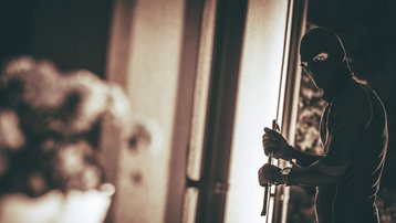 Maskierte Person versucht nachts mit einem Werkzeug in ein Haus einzubrechen