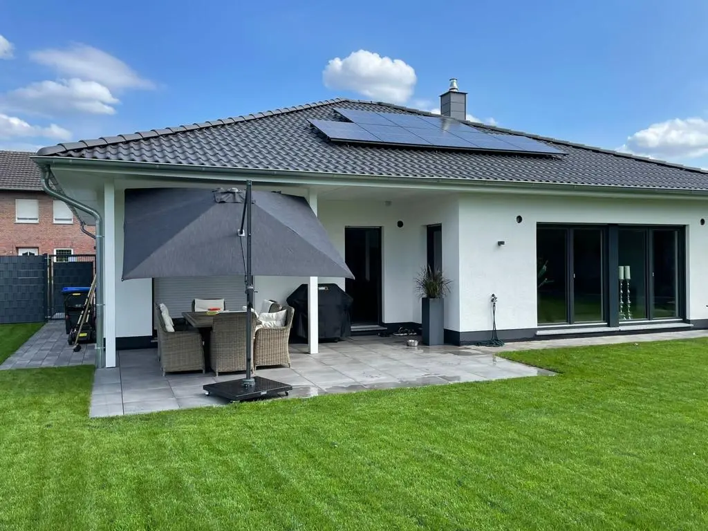 Moderner Bungalow mit Terasse und Markise Moderner Bungalow mit Terrasse, Markise und gepflegtem Rasen im Garten.