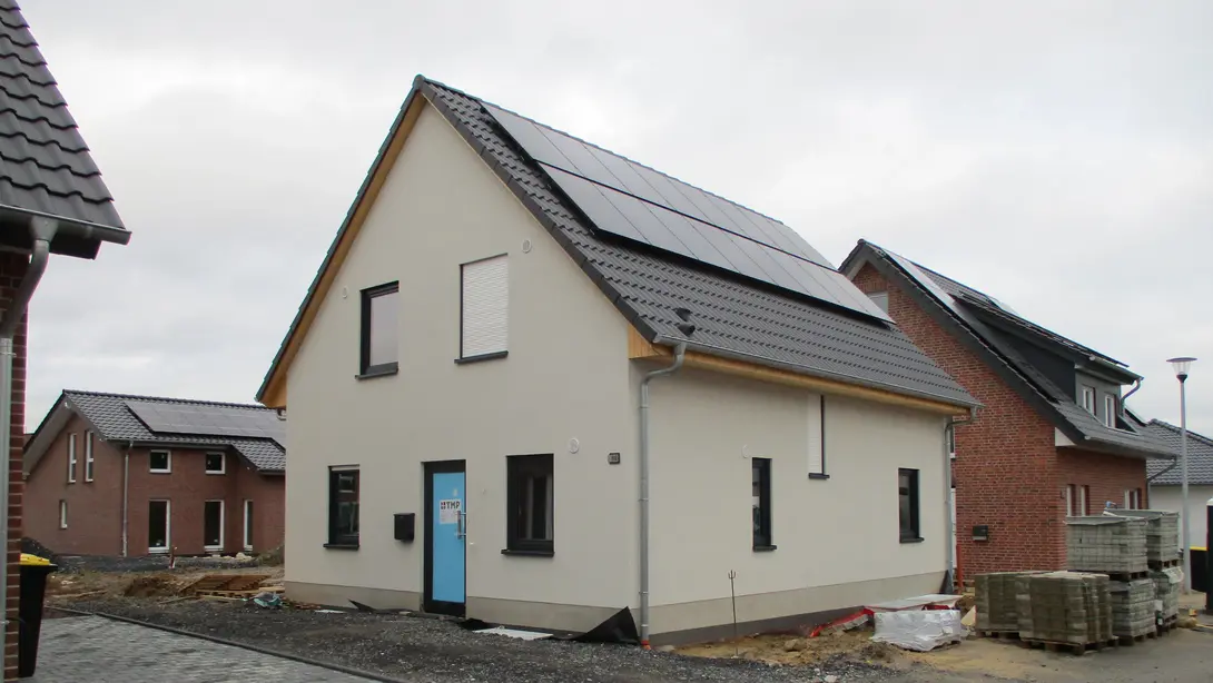 Einfamilienhaus mit Photovoltaikanlage im Baugebiet Einfamilienhaus mit heller Fassade, Satteldach, Photovoltaikanlage und Außenbereich im Baugebiet