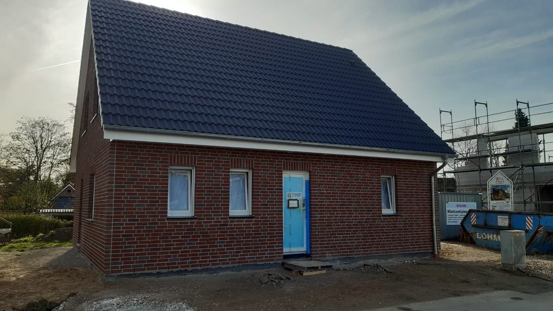 Neubau eines Massivhauses mit roter Klinkerfassade und Satteldach während der Bauphase