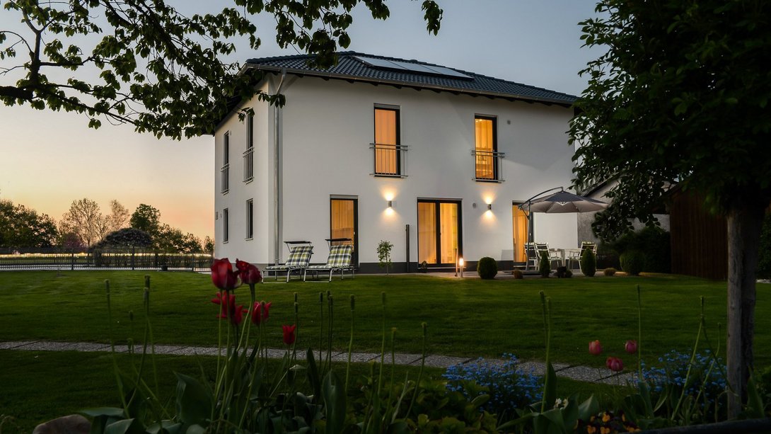 Modernes Einfamilienhaus mit Garten in Metelen – Thielker MassivHaus Modernes Einfamilienhaus mit Garten und Terrasse am Abend in Metelen – Massivhaus von Thielker MassivHaus