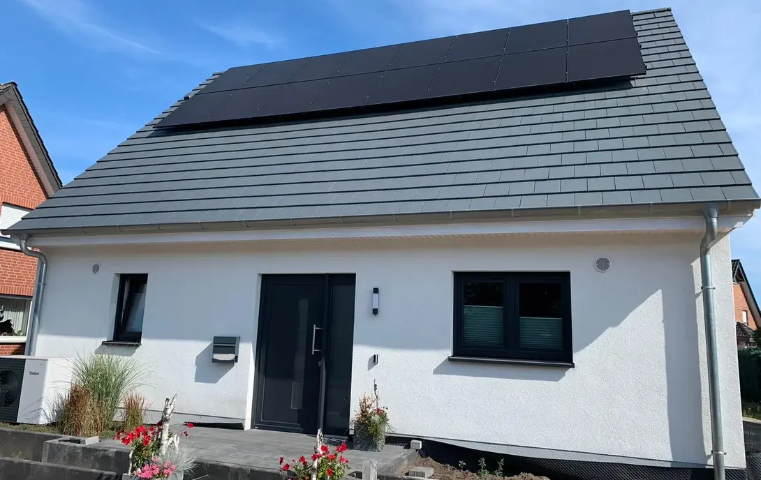 Einfamilienhaus mit Photovoltaikanlage und Satteldach Einfamilienhaus mit weißer Fassade, dunklem Satteldach, Photovoltaikanlage und Vorgarten