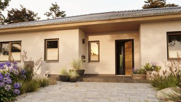 Moderner Bungalow mit einladendem Eingangsbereich Moderner Bungalow mit heller Fassade, offenem Eingangsbereich, gepflasterter Zufahrt und liebevoll angelegtem Vorgarten