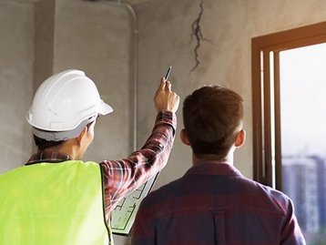 Bauleiter und Bauherr prüfen gemeinsam den Rohbau eines Hauses