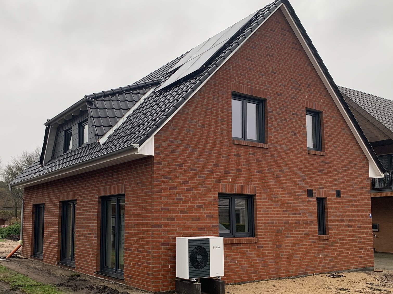 Neubau eines Einfamilienhauses aus rotem Klinker mit Satteldach und Dachfenstern.
