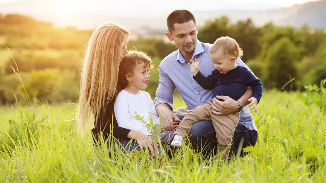 Familienfreundlich wohnen im Landkreis Emsland mit Thielker MassivHaus Familie mit zwei Kindern sitzt im Grünen im Landkreis Emsland