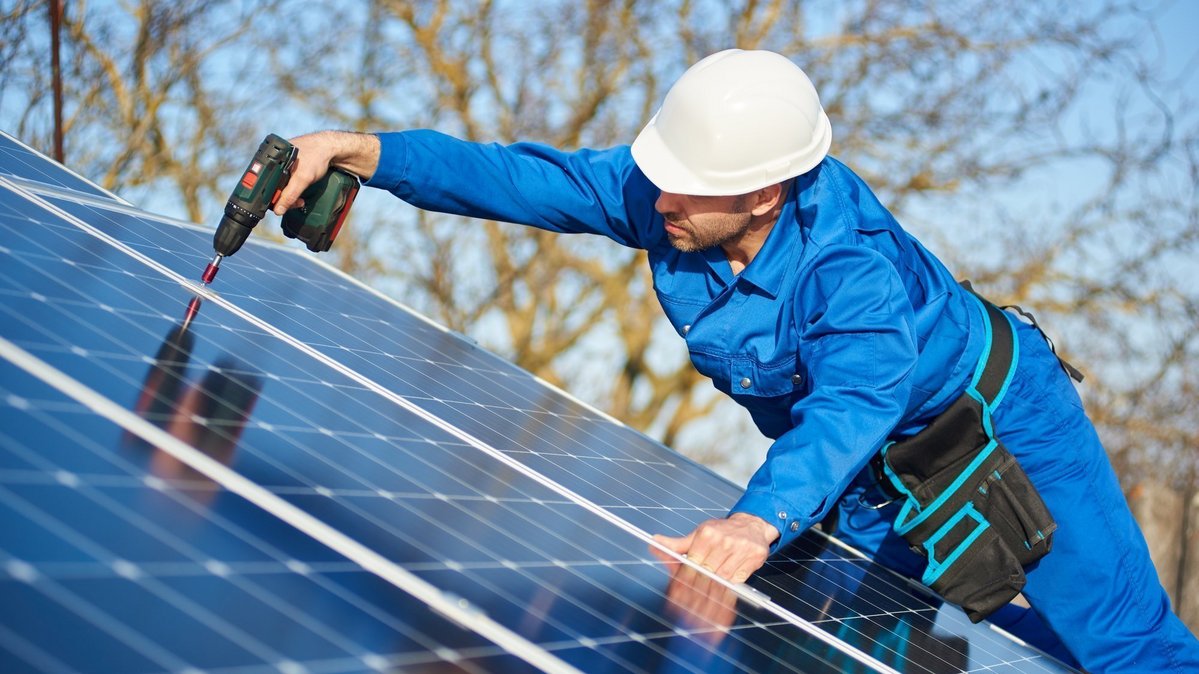 Handwerker montiert Photovoltaikmodule auf einem Dach