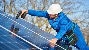 Handwerker montiert Photovoltaikmodule auf einem Dach