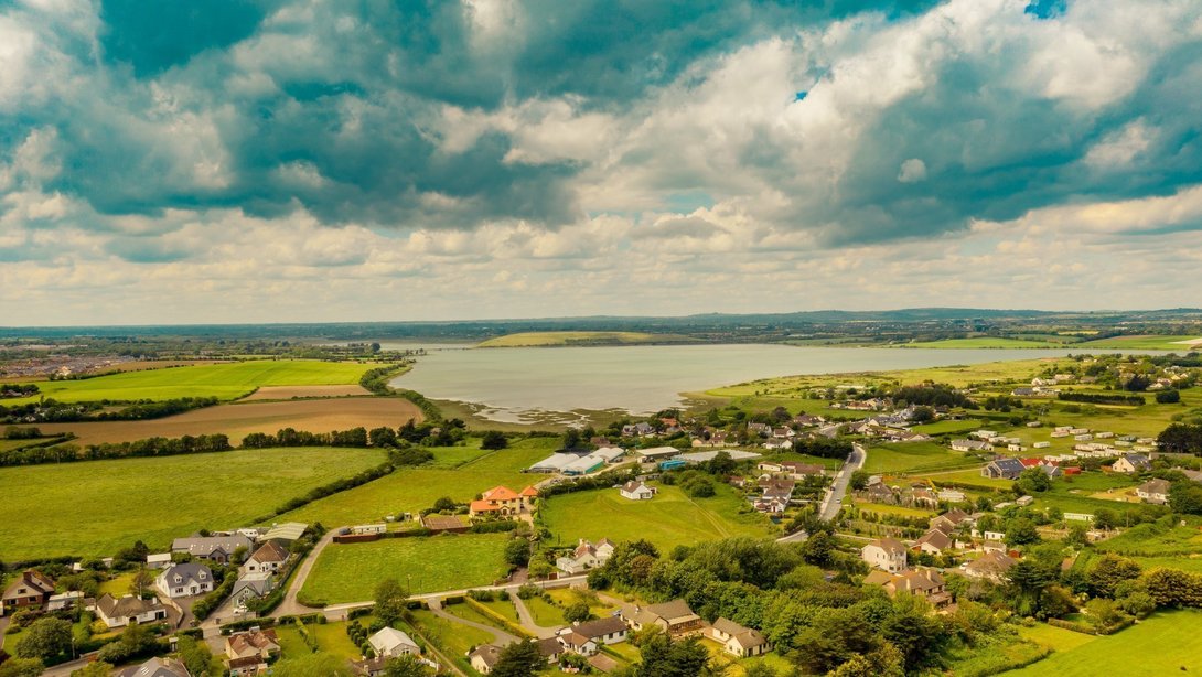 Luftaufnahme einer ländlichen Gemeinde mit Feldern, Wohnhäusern und weiter Landschaft im Münsterland.