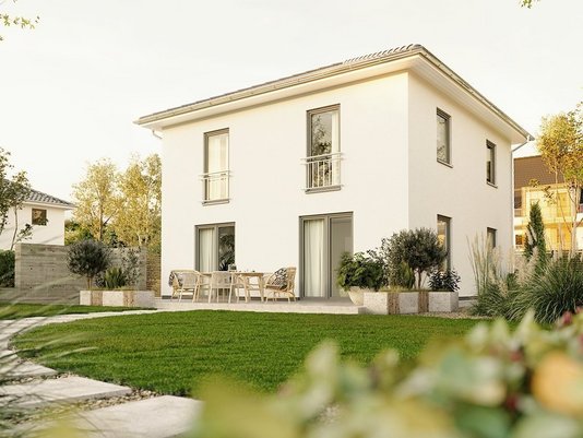 Modernes zweigeschossiges Einfamilienhaus von Thielker MassivHaus mit heller Fassade, Flachdach, Terrasse und gepflegtem Garten.