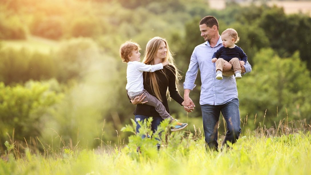 Familienfreundlich wohnen im Baugebiet Vietsesch Familie steht im Grünen bei Sonnenuntergang als Symbolbild für familienfreundliches Wohnen im Baugebiet Vietsesch in Metelen