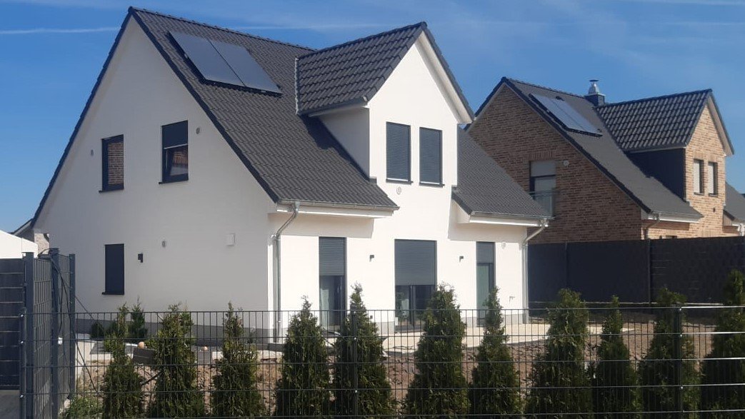 Moderne Einfamilienhäuser mit Satteldach und Solaranlagen in einem Neubaugebiet – Massivhäuser im Münsterland.