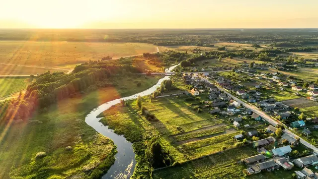 Ländliche Wohnlage mit Fluss und Sonnenuntergang Luftaufnahme einer ländlichen Region mit Fluss, Feldern, Wohngebiet und Sonnenuntergang