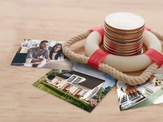 Münzstapel mit Rettungsring und Hausbildern – Symbol für sichere Baufinanzierung in Horstmar.