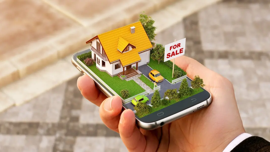 Immobilienangebot und Hauskauf digital planen Hand hält ein Smartphone mit digitalem Hausmodell und Verkaufsschild als Symbol für Immobilienangebot und Grundstückssuche