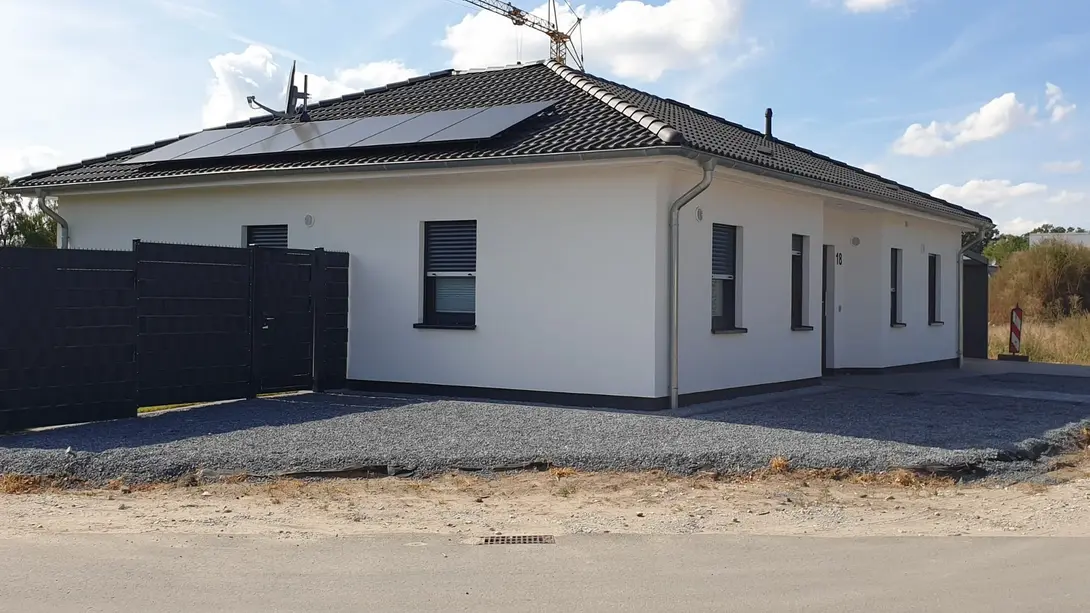 Moderner Bungalow mit Photovoltaik und Walmdach Moderner Bungalow mit weißer Fassade, Walmdach, Photovoltaikanlage und geschottertem Außenbereich