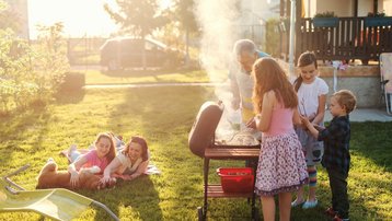 Familie und Kinder verbringen gemeinsam Zeit beim Grillen im Garten