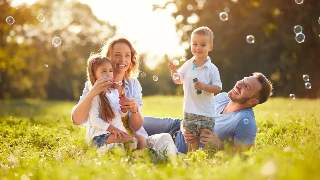 Familie spielt mit Seifenblasen auf einer Wiese als Symbolbild für familienfreundliches Wohnen im Baugebiet Hopsten-Schale Schützenstraße Familie spielt mit Seifenblasen auf einer Wiese als Symbolbild für familienfreundliches Wohnen im Baugebiet Hopsten-Schale Schützenstraße