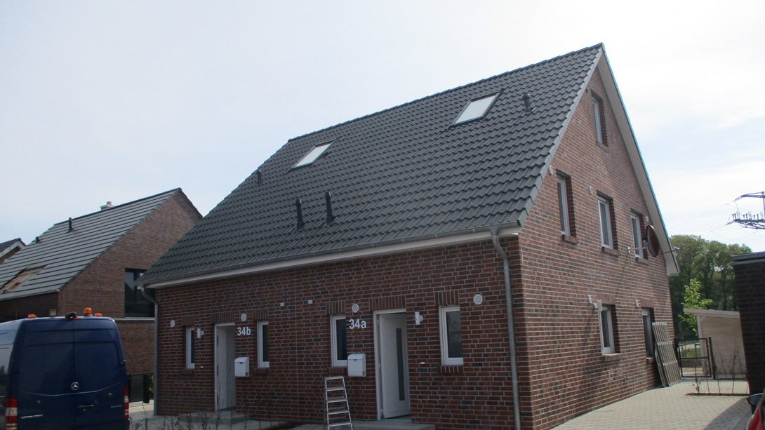 Modernes Doppelhaus mit roter Klinkerfassade und Satteldach in neuem Wohngebiet